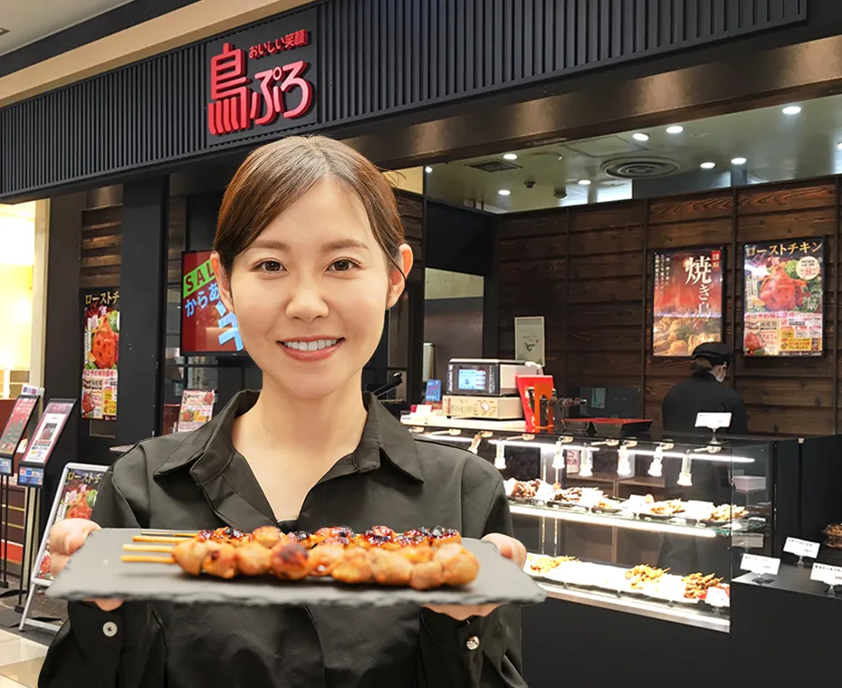 店舗前で焼き鳥を持っている定員さん